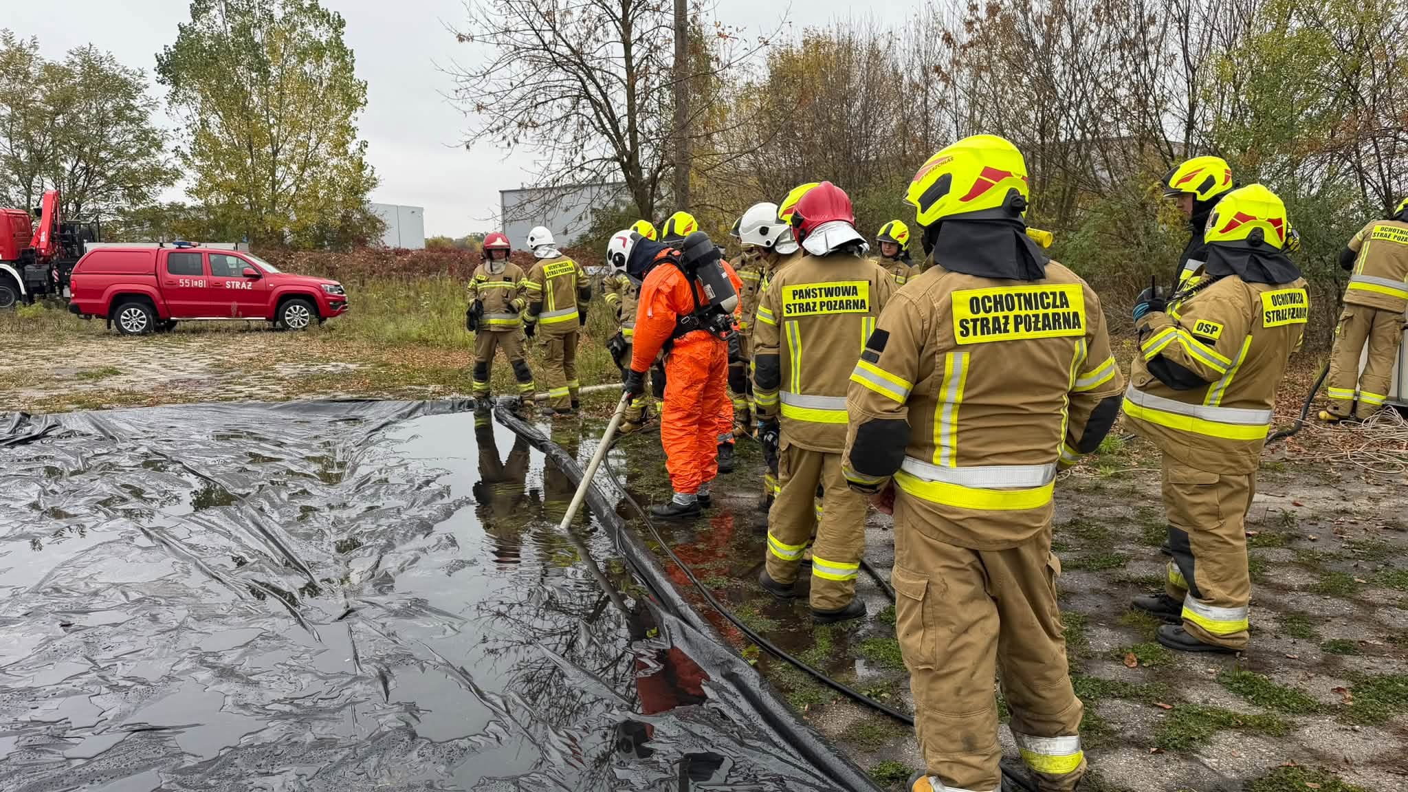 Strażacy prowadzą ćwiczenia przy przygotowanym stanowisku dekontaminacyjnym.