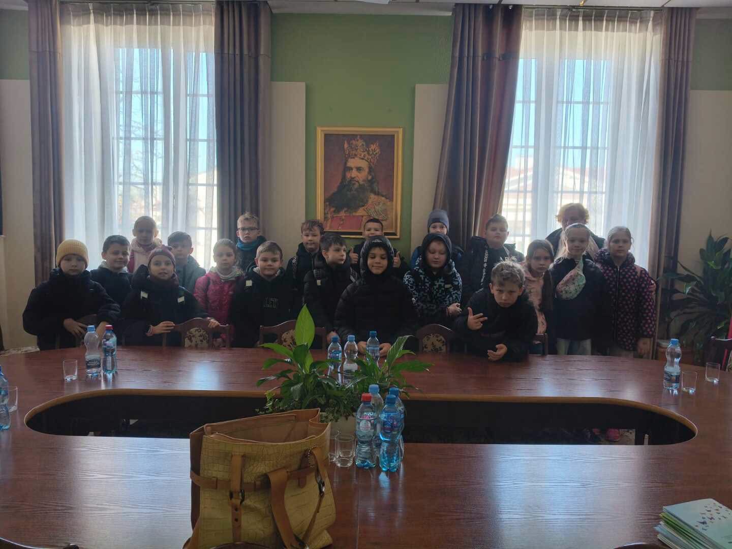 Grupa uczniów w sali ratuszowej, w tle portret króla.