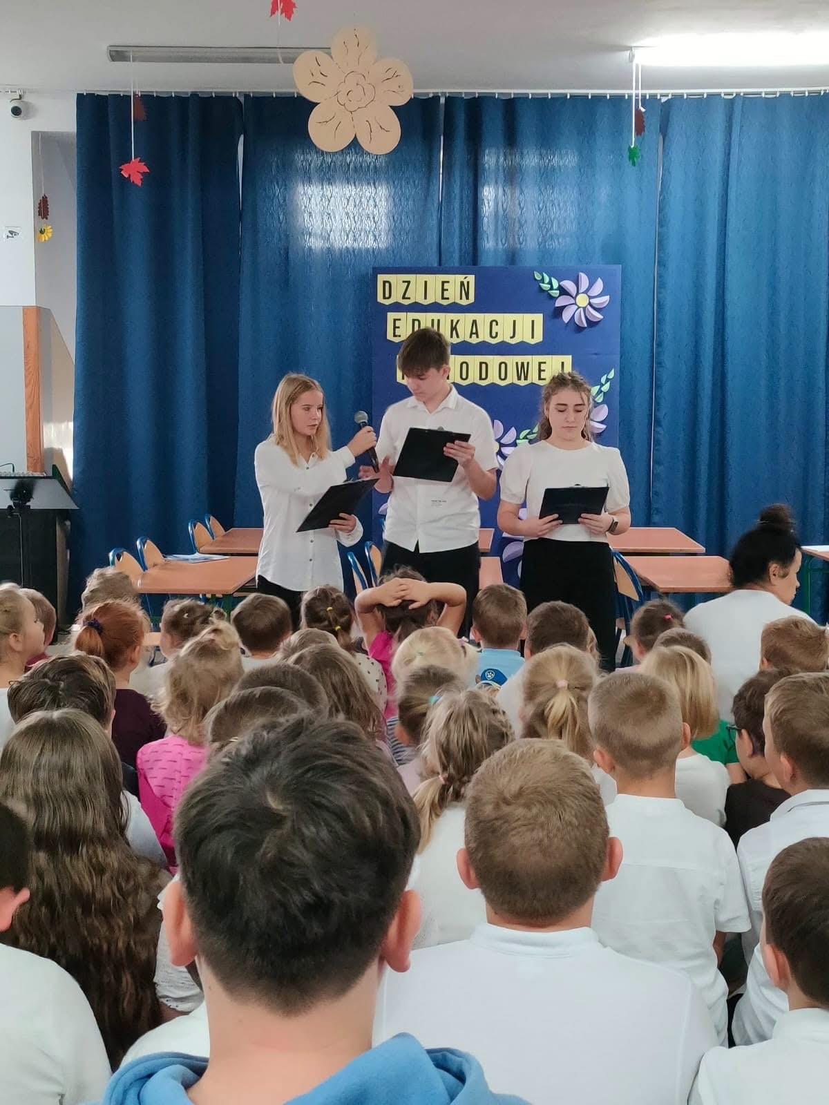 Troje uczniów prowadzi uroczystość z okazji Dnia Edukacji Narodowej. Fot. Szkoła Podstawowa im. Henryka Sienkiewicza w Wierzchlesie.